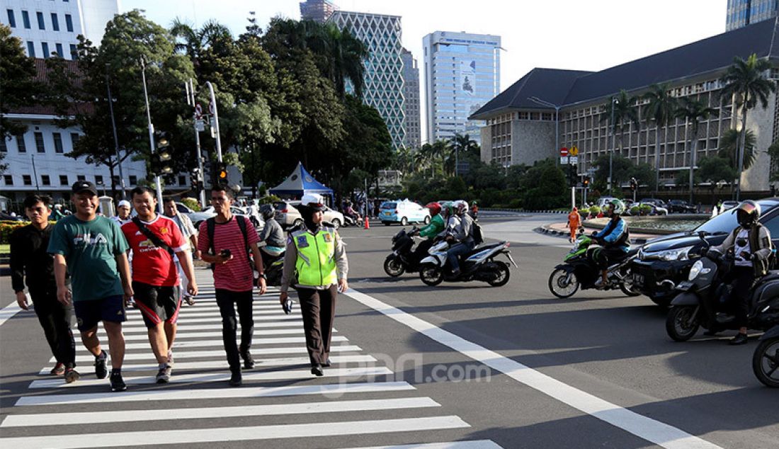 Pejalan kaki saat menyeberang jalan menggunakan Zebra Cross di Jalan Medan Merdeka Selatan, Jakarta, Jumat (21/2). - JPNN.com