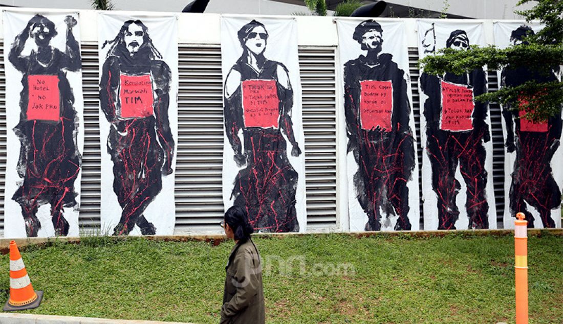 Seorang warga melintas di depan Mural Save TIM di Taman Ismail Marzuki, Jakarta, Selasa (3/3). - JPNN.com