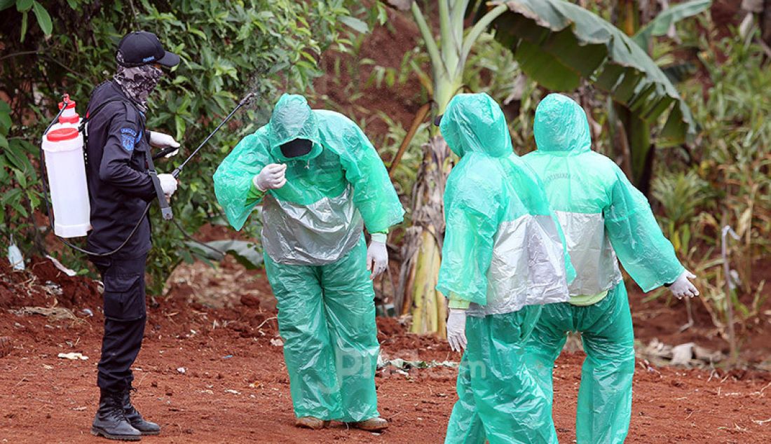 Petugas menyemprotkan cairan disinfektan kepada petugas makam usai memakamkan jenazah korban Covid-19 yang dimakamkan di TPU Pondok Ranggon, Cipayung, Jakarta Timur, Rabu (1/4). - JPNN.com