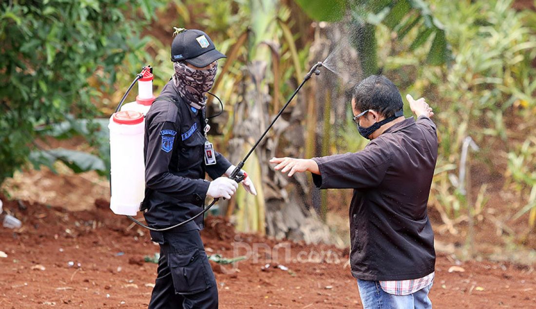 Petugas menyemprotkan cairan disinfektan kepada peziarah usai menghadiri pemakaman jenazah korban Covid-19 di TPU Pondok Ranggon, Cipayung, Jakarta Timur, Rabu (1/4). - JPNN.com