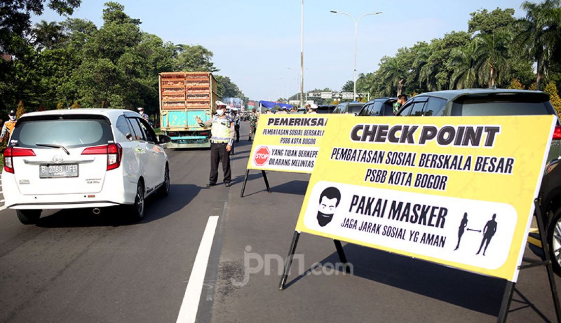 Petugas gabungan melakukan pemeriksaan kendaraan di Pintu Keluar Tol Baranangsiang, Bogor, Jawa Barat, Rabu (15/4). Pemeriksaan bertujuan menghimbau pengendara untuk menggunakan masker dan posisi duduk sesuai PSBB. - JPNN.com