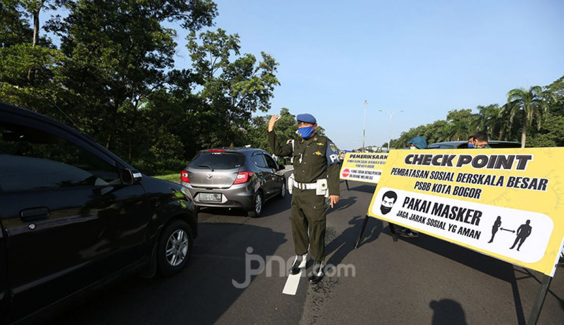 Petugas gabungan melakukan pemeriksaan kendaraan di Pintu Keluar Tol Baranangsiang, Bogor, Jawa Barat, Rabu (15/4). Pemeriksaan bertujuan menghimbau pengendara untuk menggunakan masker dan posisi duduk sesuai PSBB. - JPNN.com