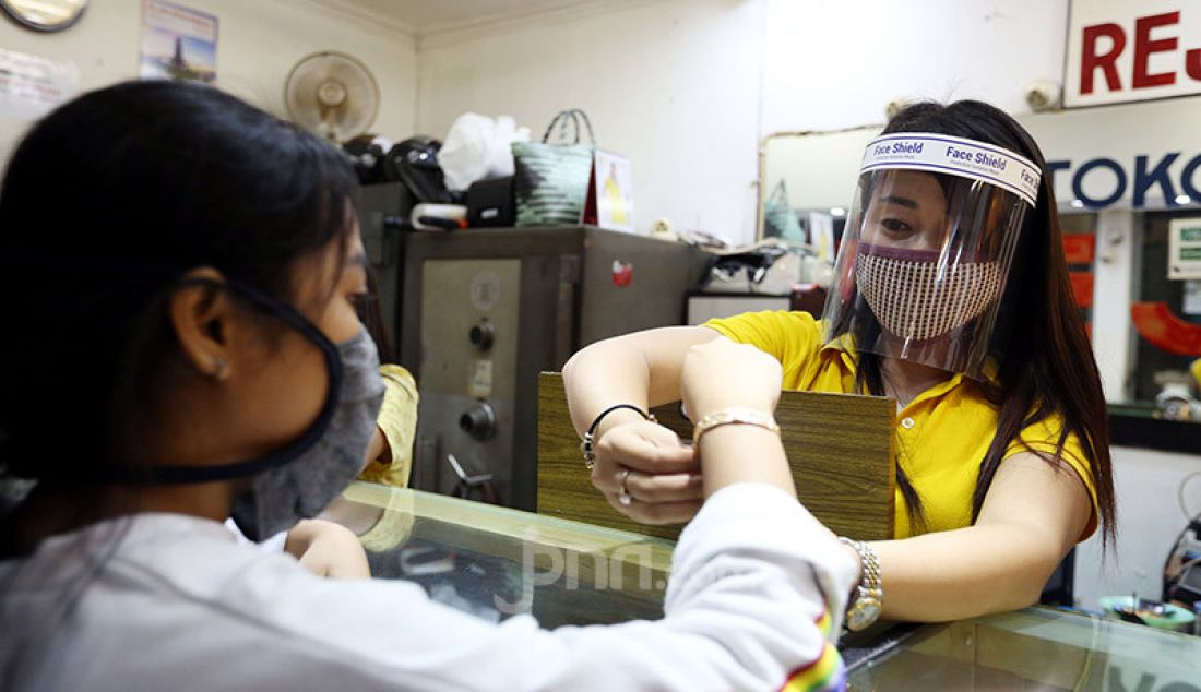 Pegawai toko menggunakan masker dan alat pelindung wajah (face shield) di toko emas Rejeki, Pasar Bogor, Senin (20/4). Penggunaan alat pelindung wajah tersebut sebagai upaya pencegahan penyebaran virus Corona (COVID-19). - JPNN.com