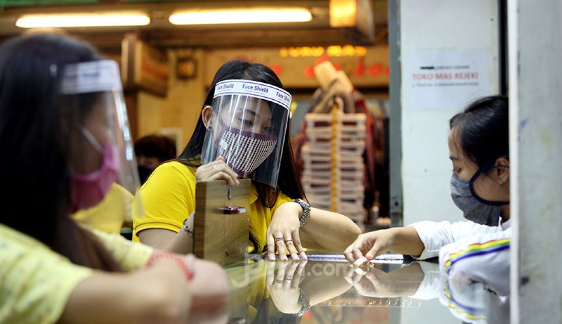 Pegawai toko menggunakan masker dan alat pelindung wajah (face shield) di toko emas Rejeki, Pasar Bogor, Senin (20/4). Penggunaan alat pelindung wajah tersebut sebagai upaya pencegahan penyebaran virus Corona (COVID-19). - JPNN.com