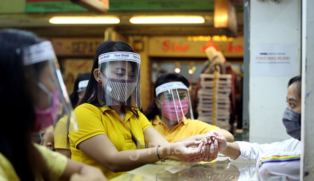 Pegawai toko menggunakan masker dan alat pelindung wajah (face shield) di toko emas Rejeki, Pasar Bogor, Senin (20/4). Penggunaan alat pelindung wajah tersebut sebagai upaya pencegahan penyebaran virus Corona (COVID-19). - JPNN.com