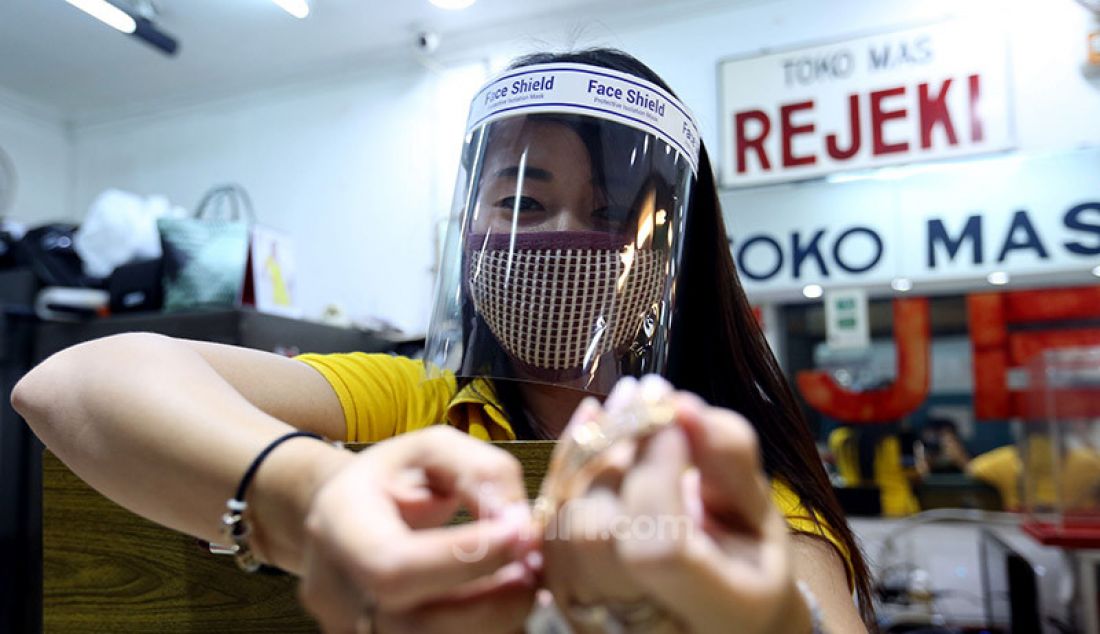 Pegawai toko menggunakan masker dan alat pelindung wajah (face shield) di toko emas Rejeki, Pasar Bogor, Senin (20/4). Penggunaan alat pelindung wajah tersebut sebagai upaya pencegahan penyebaran virus Corona (COVID-19). - JPNN.com