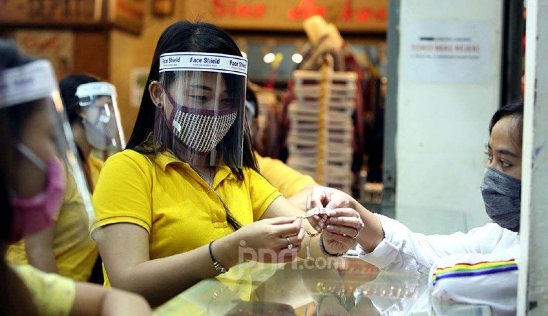 Pegawai toko menggunakan masker dan alat pelindung wajah (face shield) di toko emas Rejeki, Pasar Bogor, Senin (20/4). Penggunaan alat pelindung wajah tersebut sebagai upaya pencegahan penyebaran virus Corona (COVID-19). - JPNN.com