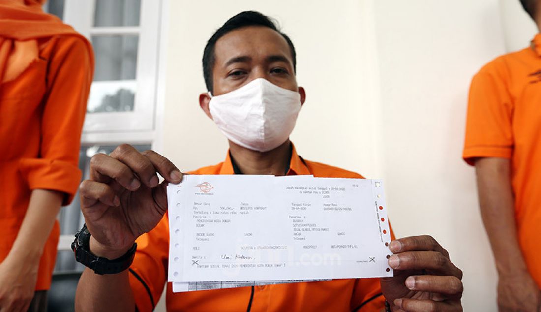 Petugas pos saat menunjukkan bukti penerima bantuan sosial tunai non DTKS yang terdampak Covid 19 dari Pemkot Bogor di Kecamatan Bogor Utara, Jawa Barat, Selasa (28/4). Bantuan tersebut sebesar Rp 500.000. - JPNN.com