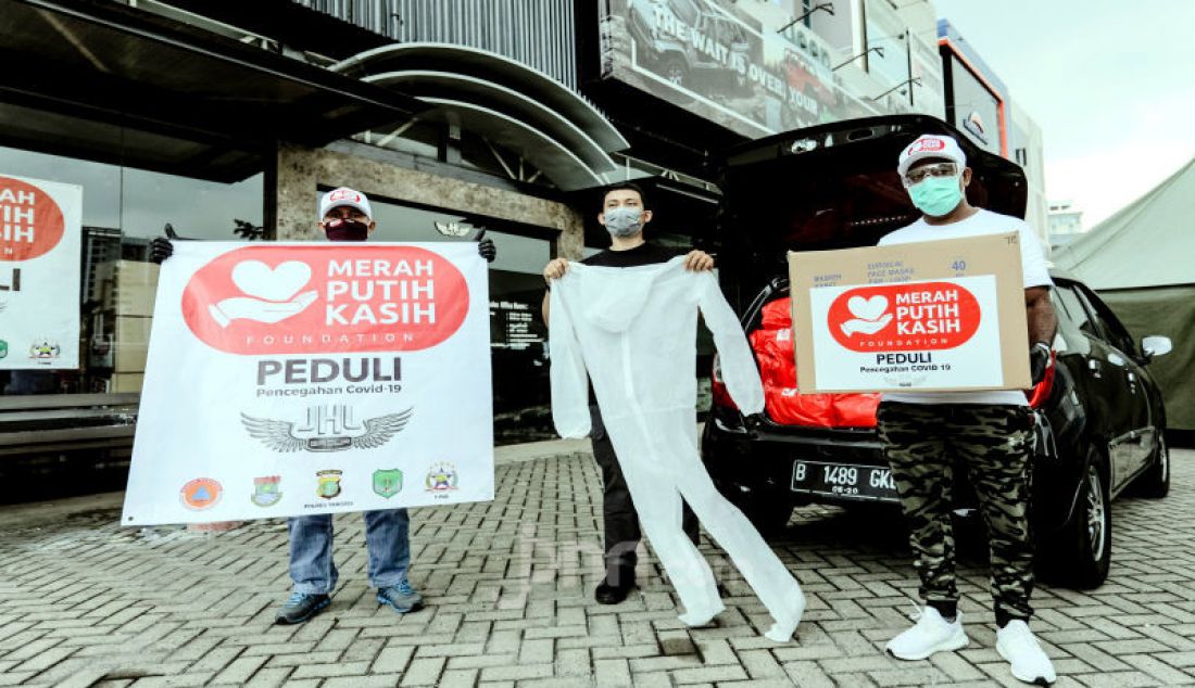 Koordinator Distribusi Posko Merah Putih Kasih Foundation JHL Group Marcelinus Enggala (kanan) menyerahkan bantuan kepada Pewarta Foto Indonesia (PFI) Pusat di Tangerang, Minggu (3/5). - JPNN.com