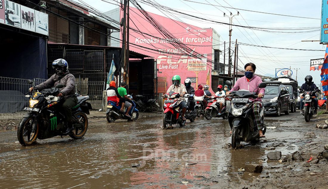 Pengendara roda dua dan emapt melintas jalan berlubang yang tergenang air dan lumpur di Jalan Raya Bojonggede, Bogor Senin (11/5). Jalan rusak tersebut merupakan jalan penghubung antara Citayam dengan Bojonggede. - JPNN.com