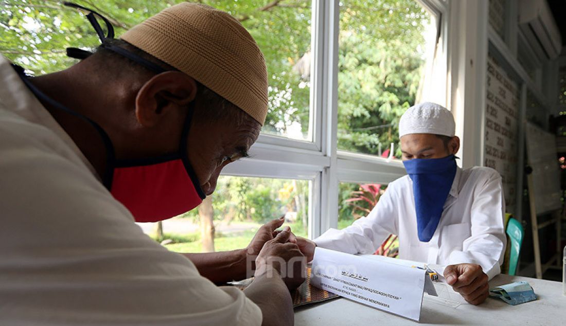 Petugas menerima pembayaran zakat fitrah di Mushola Al Ijabah, Kamis (14/5). Memasuki 10 hari terakhir bulan Ramadhan, warga mulai menyetorkan zakat fitrah di tengah pandemi Covid-19. - JPNN.com