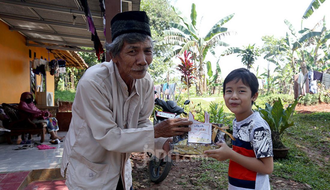 Anak TK membuat bingkisan parcel dari jajanannya dan memberikannya kepada seorang kakek yang sehari-hari bekerja sebagai petugas kebersihan, Tajur Halang, Kabupaten Bogor, Minggu (17/5). - JPNN.com