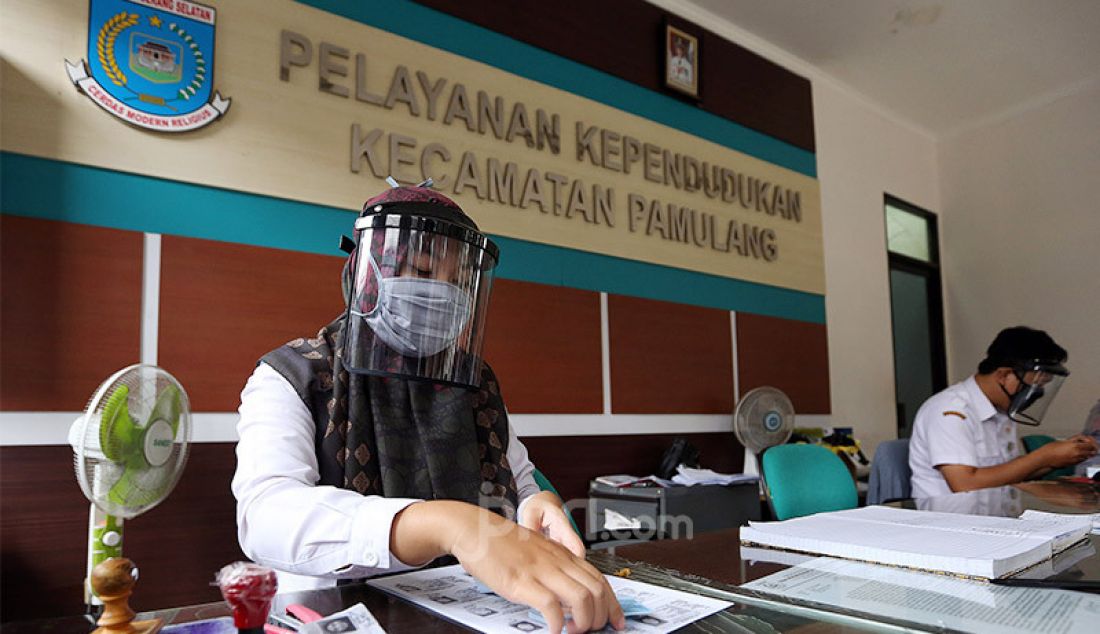 Petugas Kependudukan dan Catatan Sipil menggunakan pelindung wajah di kantor kecamatan Pamulang, Tangerang Selatan, Rabu (3/6). Sejumlah kantor pelayaann pemerintah melaksanakan protokol kesehatan yang ketat. - JPNN.com