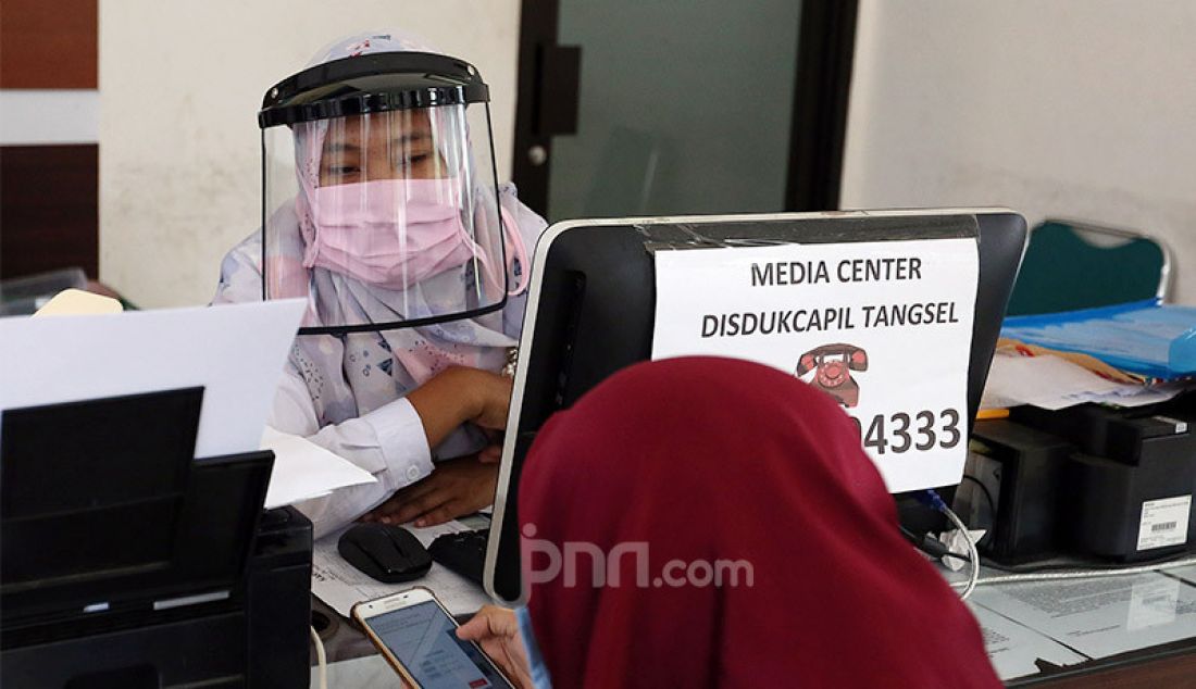 Petugas Kependudukan dan Catatan Sipil menggunakan pelindung wajah saat melayani warga di kantor kecamatan Pamulang, Tangerang Selatan, Rabu (3/6). - JPNN.com