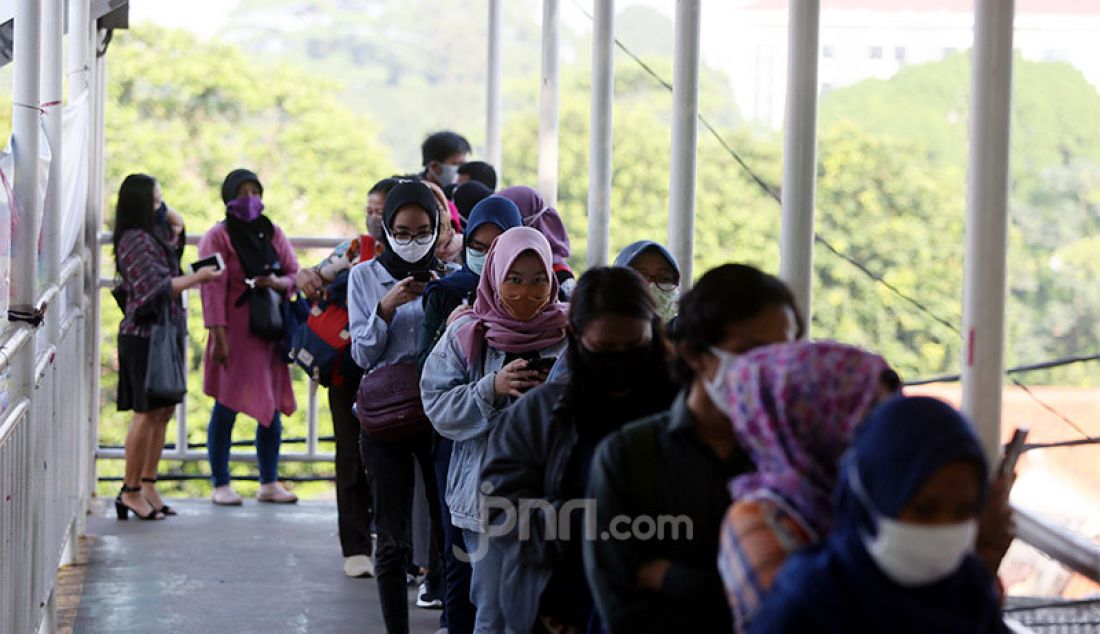 Calon penumpang KRL saat mengantri di luar stasiun Lenteng Agung, Jakarta, Senin (8/6). Mereka mengantri karena adanya pembatasan penumpang. - JPNN.com