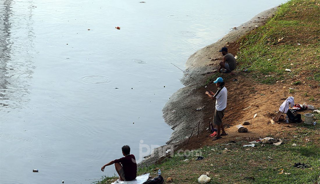 Warga melakukan aktivitas memancing di Kanal Banjir Barat, Jakarta, Selasa (9/6). Fase pertama PSBB transisi di Ibukota dimanfaatkan sejumlah warga untuk aktivitas memancing. - JPNN.com