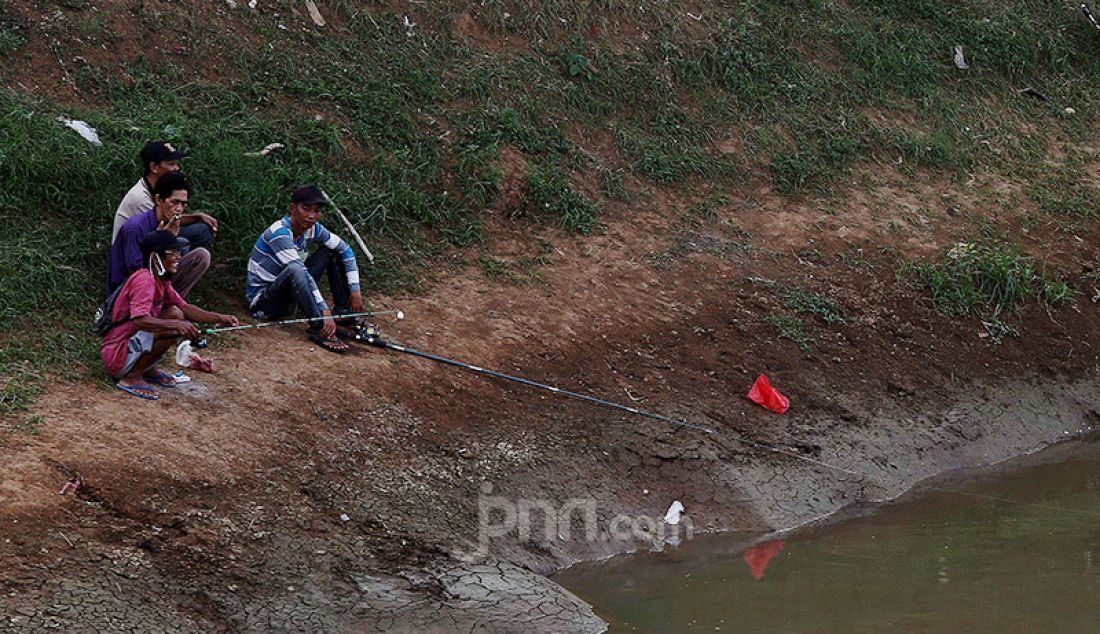 Warga melakukan aktivitas memancing di Kanal Banjir Barat, Jakarta, Selasa (9/6). Fase pertama PSBB transisi di Ibukota dimanfaatkan sejumlah warga untuk aktivitas memancing. - JPNN.com