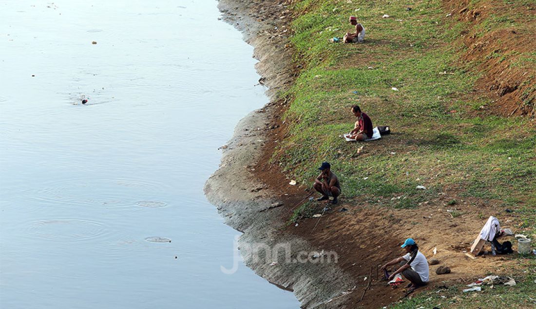 Warga melakukan aktivitas memancing di Kanal Banjir Barat, Jakarta, Selasa (9/6). Fase pertama PSBB transisi di Ibukota dimanfaatkan sejumlah warga untuk aktivitas memancing. - JPNN.com