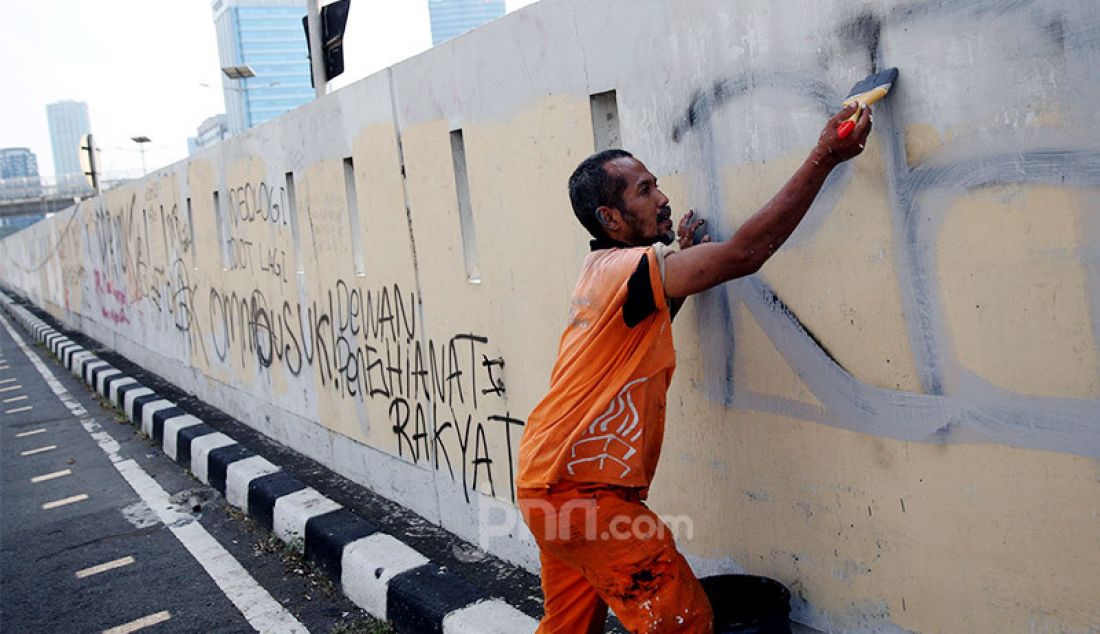 Petugas PPSU membersihkan tulisan vandalisme pasca aksi demo menolak RUU HIP dan RUU Omnibus Law Cipta Kerja di depan Gedung DPR/MPR/DPD, Jakarta, Jumat (17/7). - JPNN.com