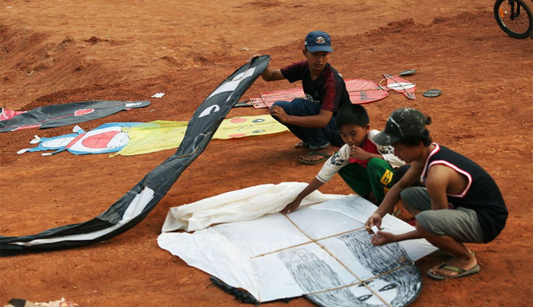 Anak-anak mempersiapkan layang-layang untuk diterbangkan di tanah lapang kawasan Sawangan, Depok, Jawa Barat, Sabtu (25/7). Bermain layang-layang menjadi alternatif hiburan tersendiri bagi anak-anak ditengah masa pandemi Covid-19 yang belum juga berakhir. - JPNN.com