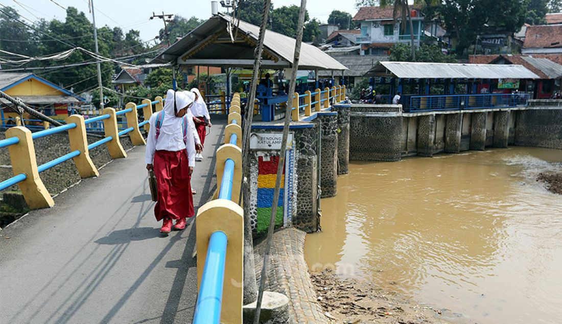 Pelajar saat berjalan di jembatan sungai Ciliwung, Bendung Katulampa, Kota Bogor, Senin (3/8). Debit air sungai Ciliwung di Bendung Katulampa, Bogor terus mengalami penyusutan sejak satu bulan terakhir di awal musim kemarau dengan kondisi aliran air hanya 100 liter per detik dan ketinggian air 0 cm. - JPNN.com