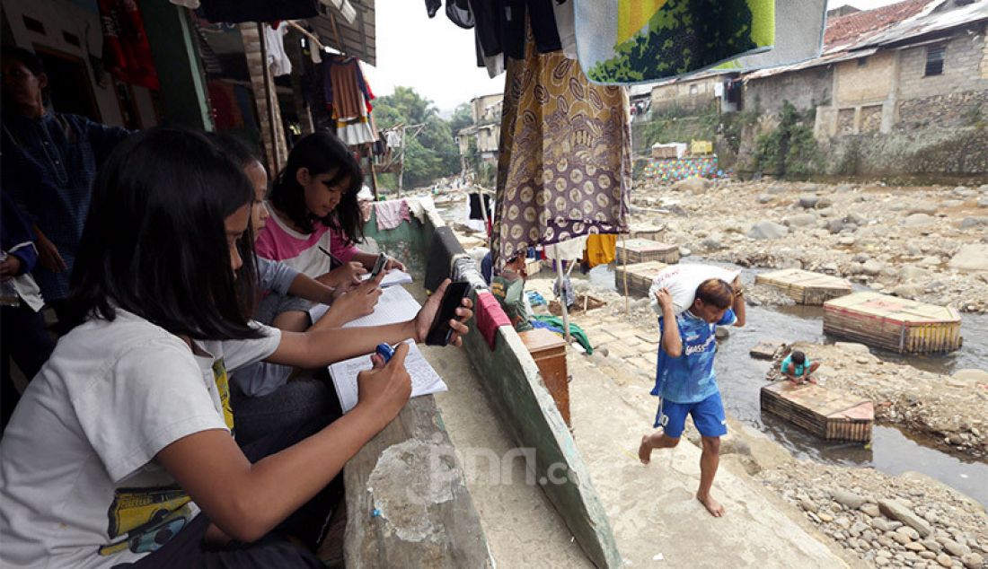 Siswi SMP Persatuan Umat Islam (PUI) Kota Bogor belajar kelompok secara daring di pinggiran sungai Ciliwung, Kampung Kebon Jukut RT 01/10, Kelurahan Babakan Pasar, Kota Bogor, Selasa (4/8). - JPNN.com