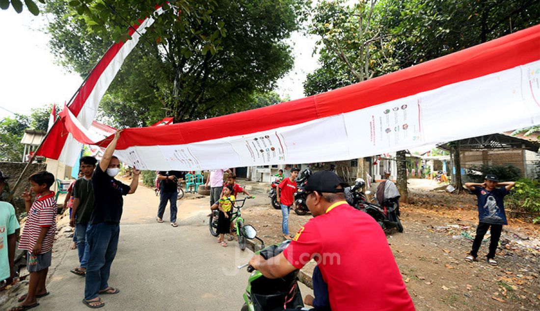 Warga membuat umbul-umbul bendera dari tas bantuan Presiden di Jalan Caringin RT3/1, Kelurahan Bedahan, Kecamatan Sawangan Kota Depok, Kamis (6/8). Mereka mebuat umbul-umbul tersebut untuk menyambut HUT ke 75 Kemerdekaan RI. - JPNN.com