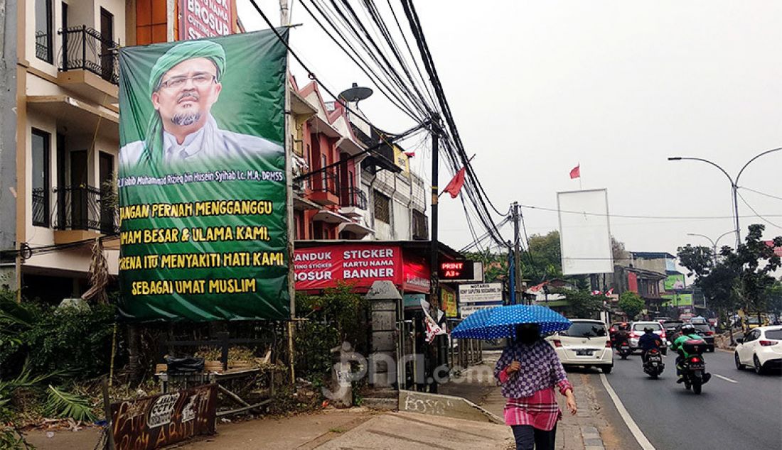 Warga melintasi spanduk Habib Rizieq Syihab di Jalan Raya Ciputat, Tangerang Selatan, Banten, Rabu (12/8). - JPNN.com