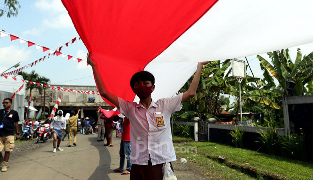 Sejumlah warga membentangkan bendera merah putih sepanjang 200 meter di Desa Cihideung Udik, Ciampea, Kabupaten Bogor, Senin (17/8). Acara tersebut dalam rangka memeriahkan peringatan HUT ke-75 Kemerdekaan Republik Indonesia. - JPNN.com