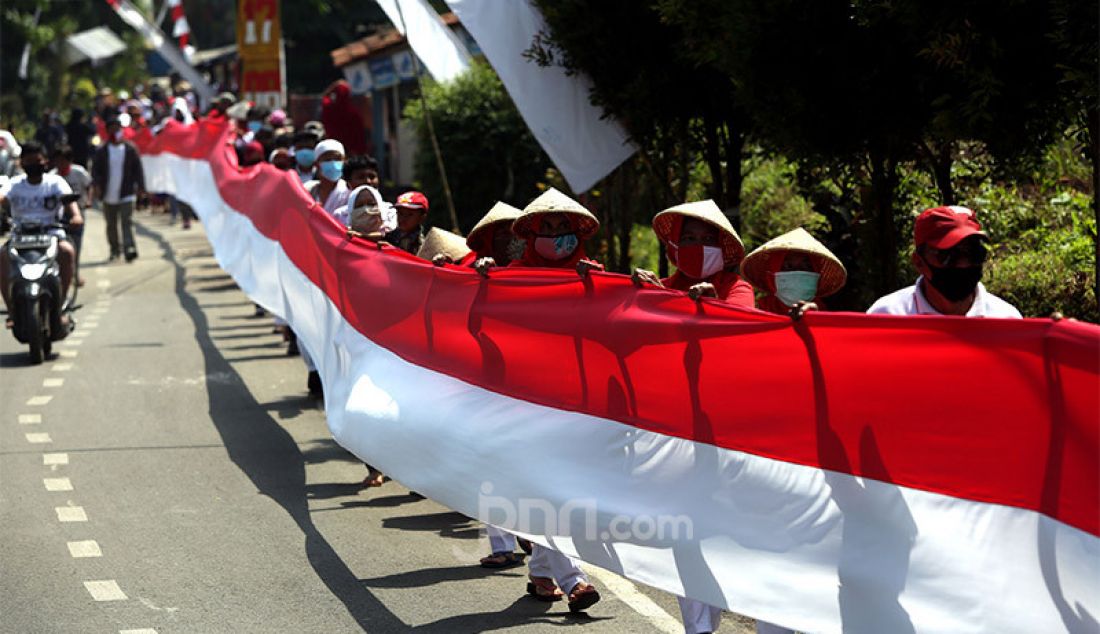 Sejumlah warga membentangkan bendera merah putih sepanjang 200 meter di Desa Cihideung Udik, Ciampea, Kabupaten Bogor, Senin (17/8). Acara tersebut dalam rangka memeriahkan peringatan HUT ke-75 Kemerdekaan Republik Indonesia. - JPNN.com