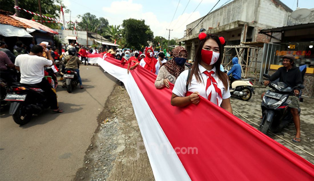 Sejumlah warga membentangkan bendera merah putih sepanjang 200 meter di Desa Cihideung Udik, Ciampea, Kabupaten Bogor, Senin (17/8). Acara tersebut dalam rangka memeriahkan peringatan HUT ke-75 Kemerdekaan Republik Indonesia. - JPNN.com