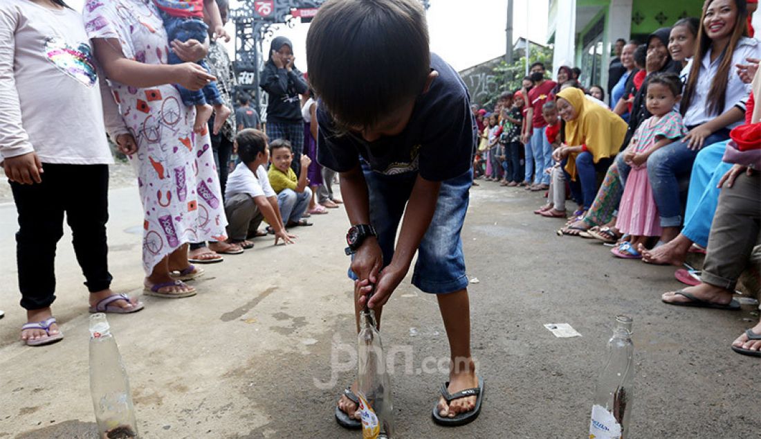 Sejumlah anak-anak mengikuti lomba 17 Agustusan masukan belut ke dalam botol di Desa Cihideung Udik, Ciampea, Kabupaten Bogor, Jawa Barat, Senin (17/8). - JPNN.com