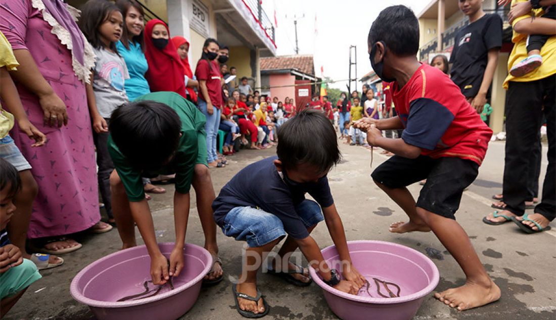 Sejumlah anak-anak mengikuti lomba 17 Agustusan masukan belut ke dalam botol di Desa Cihideung Udik, Ciampea, Kabupaten Bogor, Jawa Barat, Senin (17/8). - JPNN.com