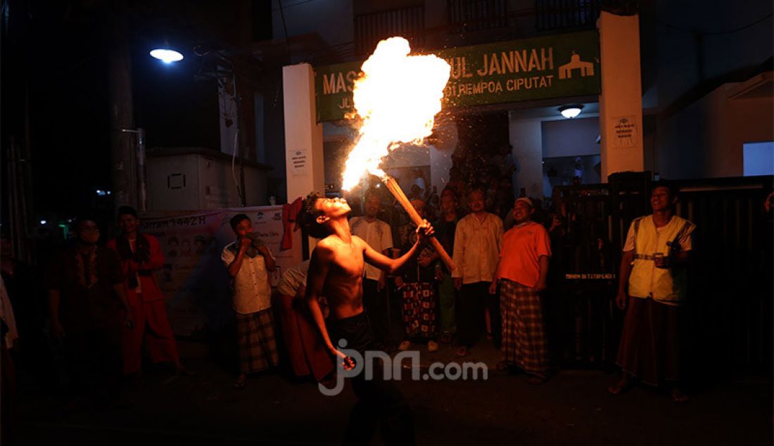 Seorang warga beratraksi menyemburkan api obor saat peringatan malam 1 Muharram 1442 H di kawasan Rempoa, Ciputat, Tangerang Selatan, Rabu (19/8). Kegiatan Gema Muharram tersebut diisi dengan berbagai kegiatan lomba, pawai obor dan permainan tradisional sepakbola api yang rutin diadakan warga untuk menjaga kerukunan dan menyambut pergantian Tahun Baru Islam. - JPNN.com