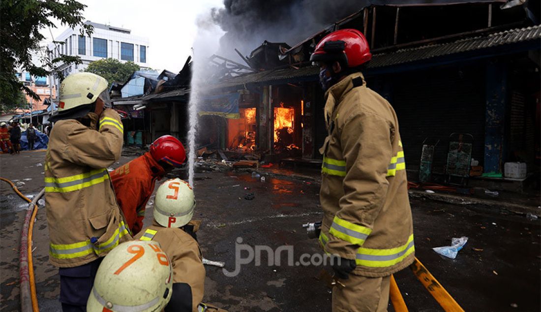 Petugas pemadam kebakaran berusaha memadamkan api di Pasar Cempaka Putih, Jakarta, Kamis (24/9). Kebakaran ini diduga karena ledakan gas elpiji. - JPNN.com