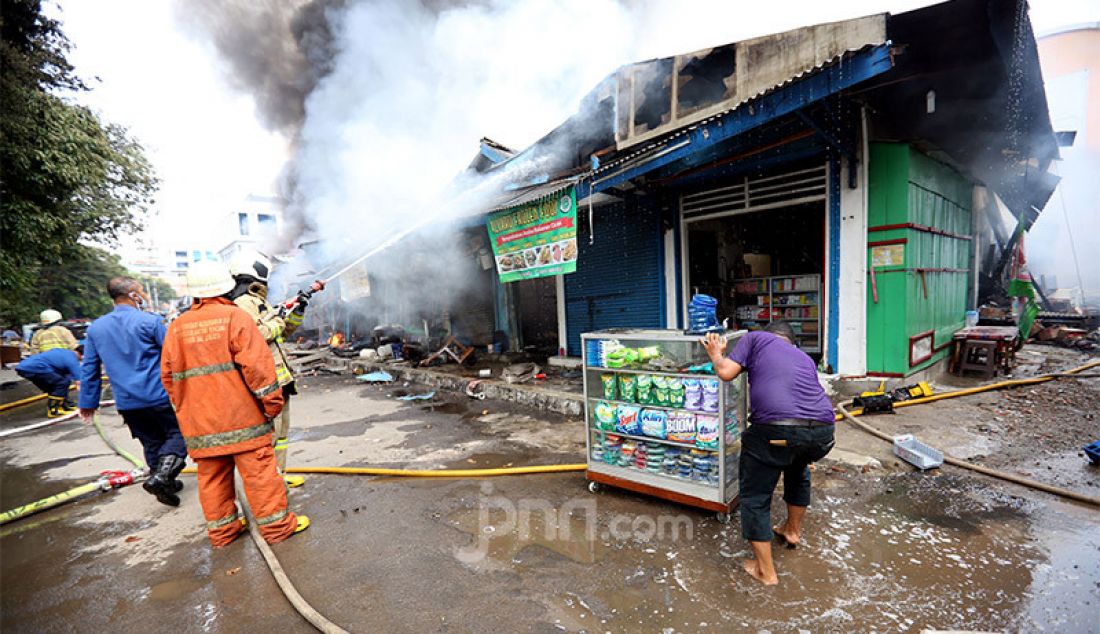 Seorang pedagang mencoba menyelamatkan barang dagangannya di tengah proses pemadaman oleh petugas pemadam kebakaran di Pasar Cempaka Putih, Jakarta, Kamis (24/9). Kebakaran ini diduga karena ledakan gas elpiji. - JPNN.com