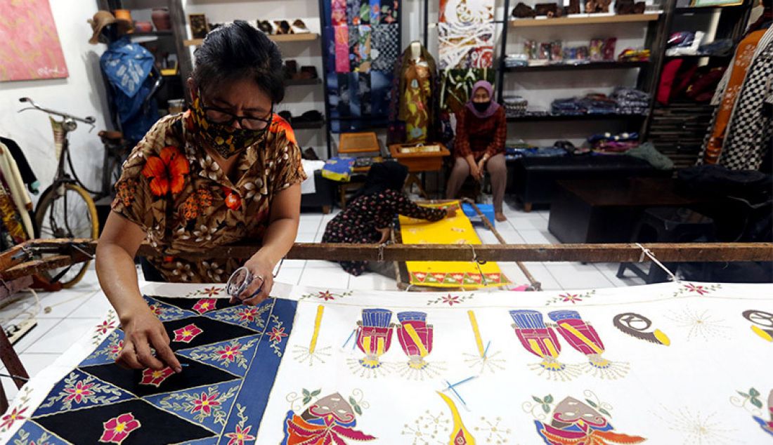 Perajin membuat batik bermotif Covid-19 di Rumah Batik Palbatu, Jakarta, Senin (19/10). Setelah sempat tutup akibat pandemi, Rumah Batik Palbatu kembali bangkit secara perlahan dengan menciptakan kain batik edisi Jakarta Terkini bergambar Covid-19 dipadu ikon-ikon khas ibu kota. - JPNN.com