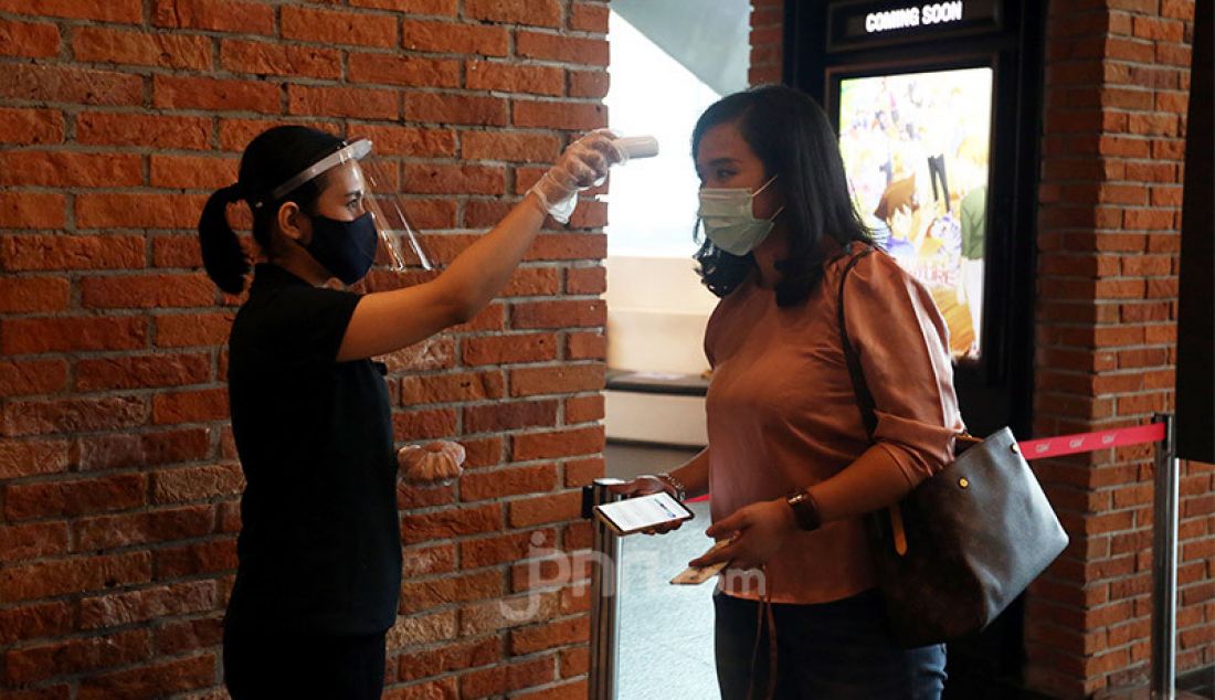 Petugas CGV Grand Indonesia, Jakarta Pusat, Rabu (21/10) memeriksa suhu tubuh pengunjung. Sejumlah bioskop di Jakarta telah beroperasi lagi setelah mendapatkan izin dari Pemprov DKI Jakarta dengan membatasi jumlah penonton maksimal 25 persen dari kapasitas. - JPNN.com