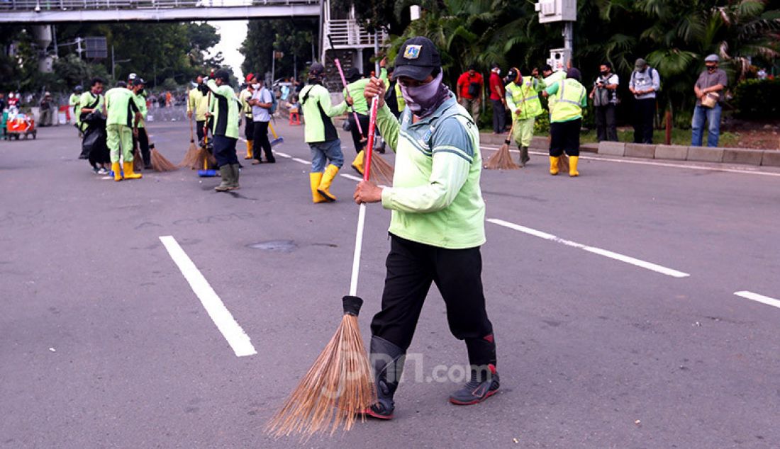 Petugas kebersihan membersihkan sampah sisa aksi demo menolak Omnibus Law Cipta Kerja di kawasan Patung Kuda, Jakarta Pusat, Kamis (22/10). - JPNN.com