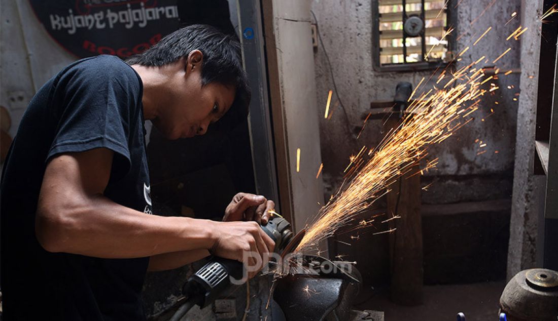 Perajin di Paneupaan Pajajaran, Katulampa, Bogor tengah mengerjakan kujang, Jumat (23/10). Produksi senjata tradisional khas Jawa Barat itu meningkat pada masa pandemi Covid-19. - JPNN.com