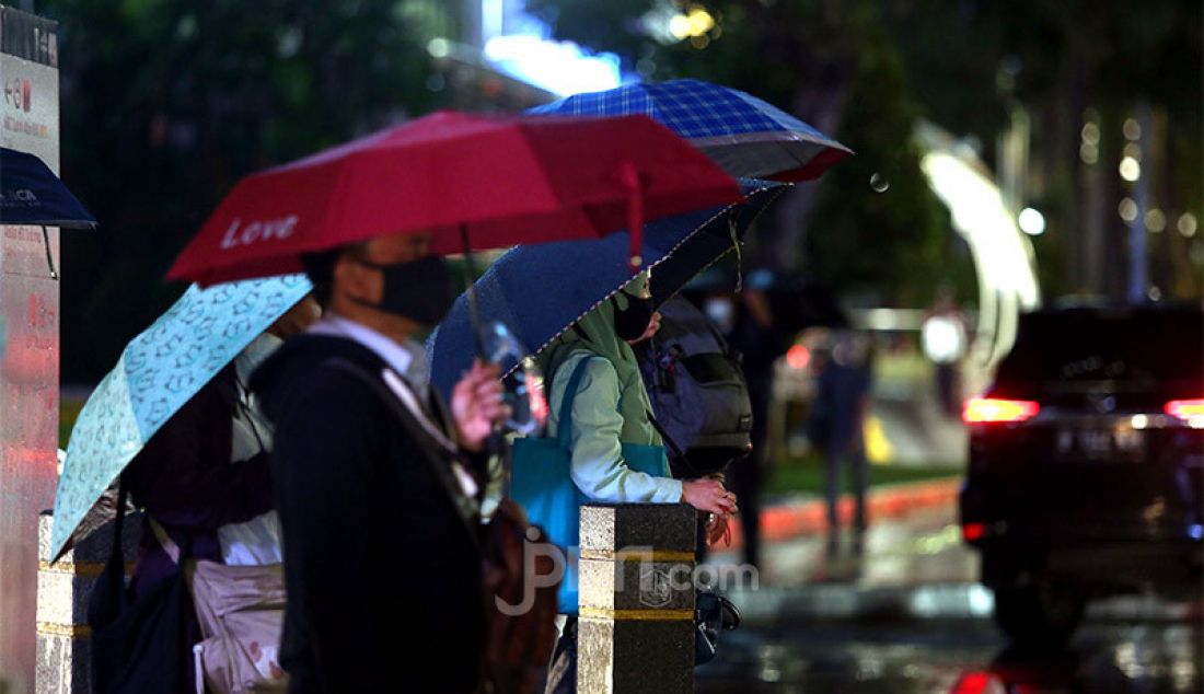Warga menggunakan payung saat hujan turun di kawasan Jalan Jendral Sudirman, Jakarta Pusat, Senin (26/10). Badan Penanggulangan Bencana Daerah (BPBD) DKI Jakarta telah mengeluarkan peringatan dini tentang curah hujan tinggi disertai angin kencang selama tiga hari. - JPNN.com