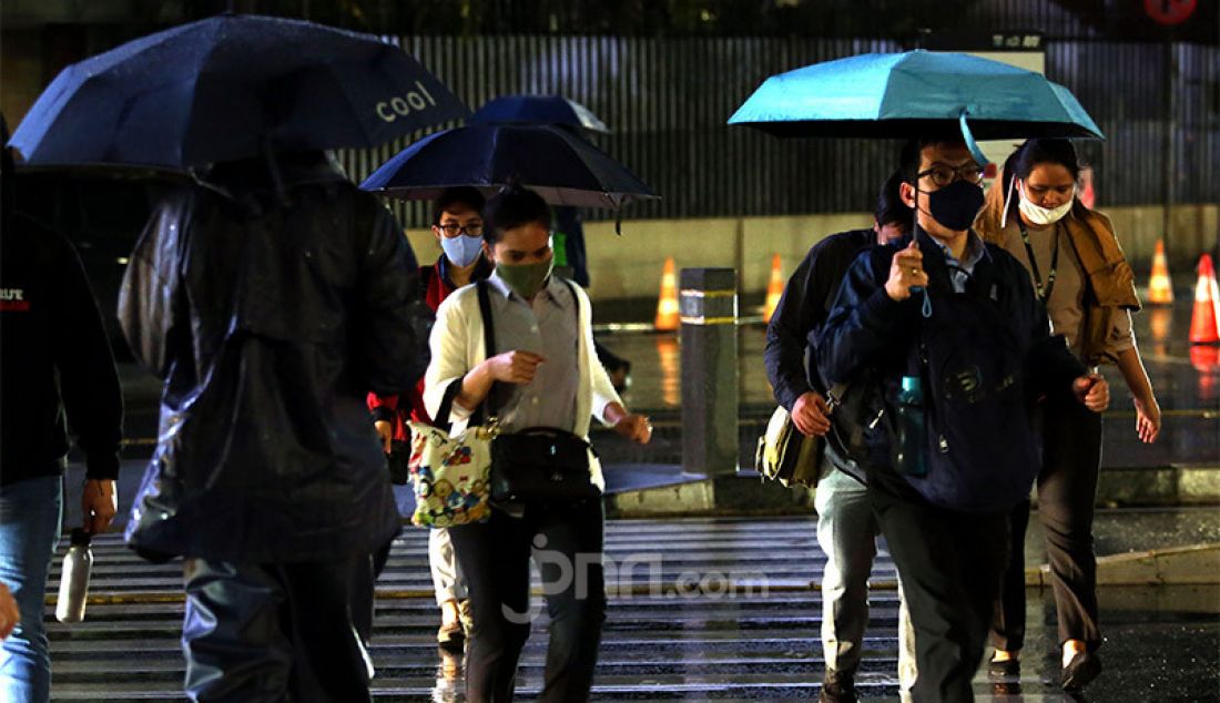 Warga menggunakan payung saat hujan turun di kawasan Jalan Jendral Sudirman, Jakarta Pusat, Senin (26/10). Badan Penanggulangan Bencana Daerah (BPBD) DKI Jakarta telah mengeluarkan peringatan dini tentang curah hujan tinggi disertai angin kencang selama tiga hari. - JPNN.com