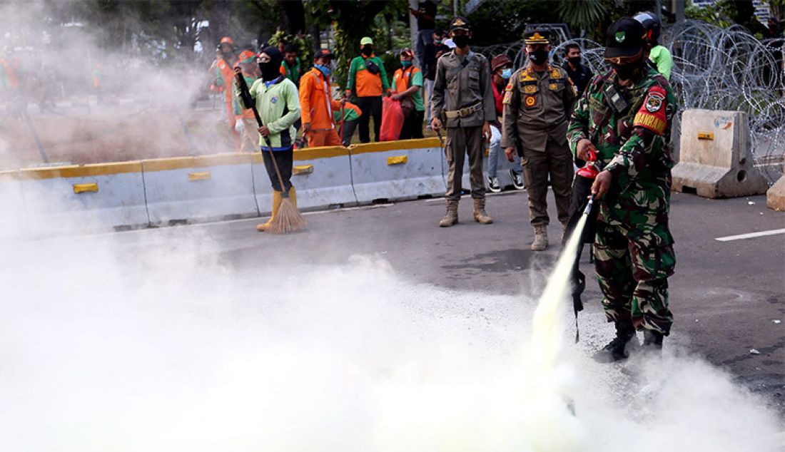 Anggota TNI memadamkan ban yang dibakar oleh massa saat aksi unjuk rasa menolak Undang-Undang Cipta Kerja di kawasan Patung Kuda, Jakarta, Rabu (28/10). - JPNN.com