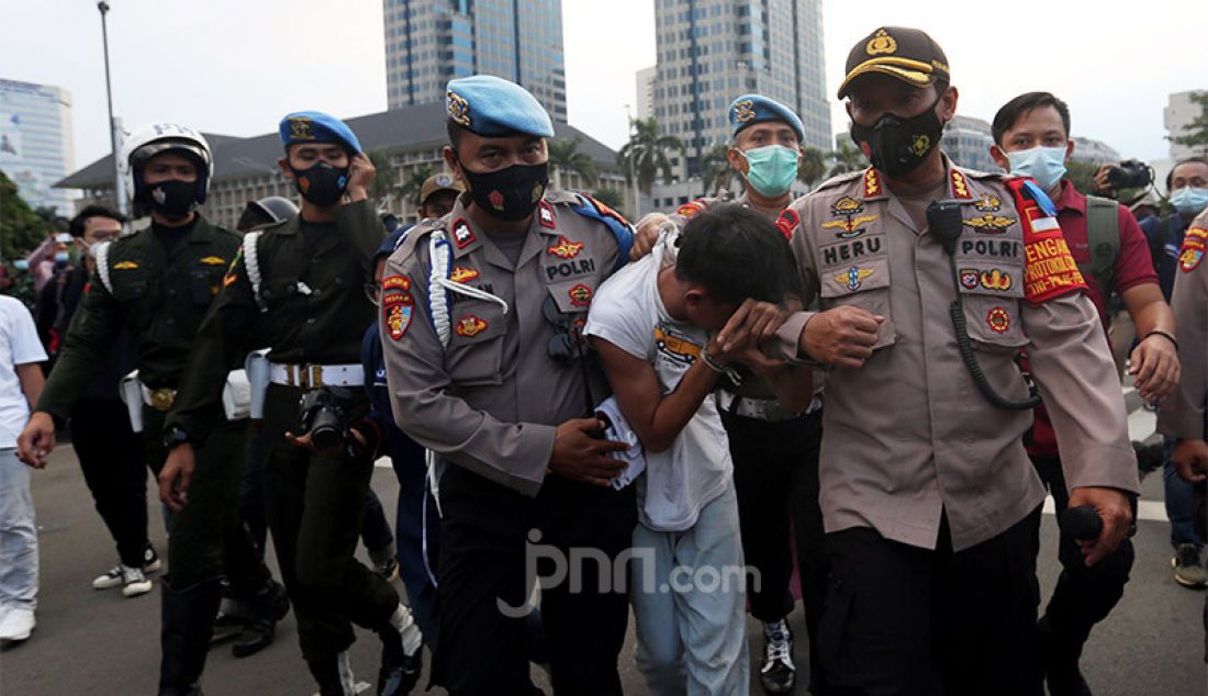 Petugas kepolisian mengamankan copet yang tertangkap tangan saat bubaran massa demo menolak UU Cipta Kerja di Kawasan Patung Kuda, Jakarta, Rabu (28/10). - JPNN.com