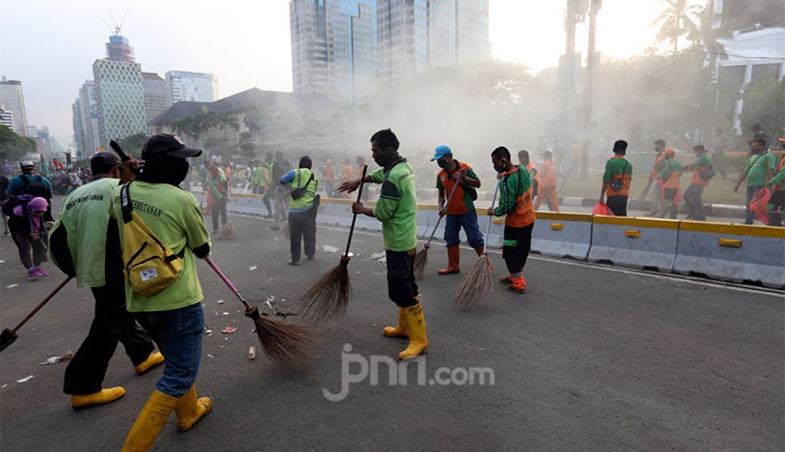 Petugas kebersihan memberikan sampah-sampah usai demo UU Cipta Kerja di Kawasan Patung Kuda, Jakarta, Rabu (28/10). - JPNN.com