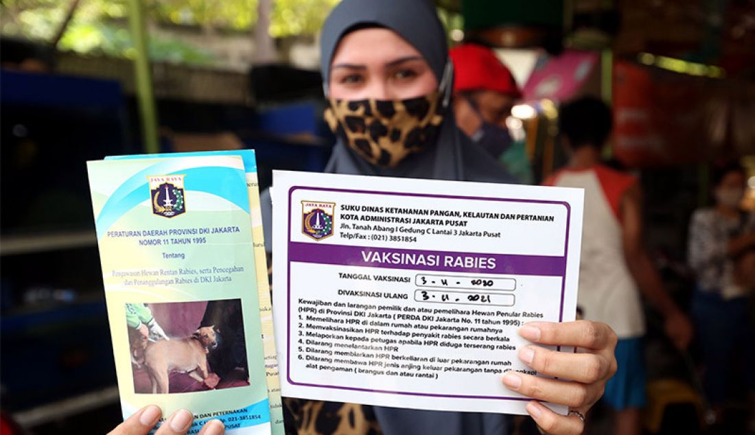 Seorang warga menunjukkan tanda bukti usai memvaksinasi hewan peliharaan miliknya, Jakarta, Selasa (3/11). Kegiatan vaksinasi itu dilakukan oleh Suku Dinas ketahanan Pangan, Kelautan dan Perikanan (KPKP) Jakarta Pusat untuk mencegah penularan Covid-19. - JPNN.com