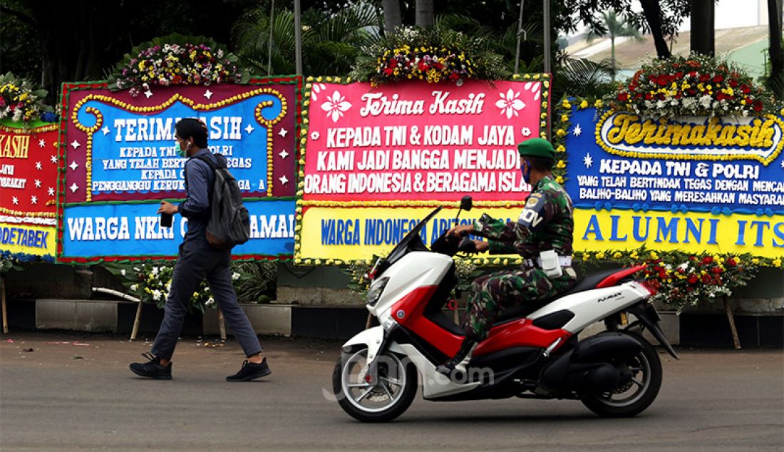 Seorang anggota TNI melintas di depan karangan bunga yang memenuhi pagar depan Markas Kodam Jaya, Jakarta Timur, Senin (23/11). Ada puluhan karangan bunga sebagai bentuk dukungan kepada Pangdam Jaya Mayjen Dudung Abdurachman yang telah bersikap tegas soal Rizieq Shihab dan Front Pembela Islam (FPI). - JPNN.com