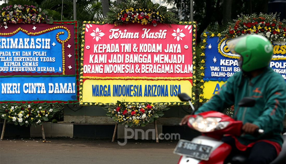 Pengguna jalan melintas di depan Markas Kodam Jaya, Jakarta Timur yang penuh dengan karangan bunga, Senin (23/11). Ada puluhan karangan bunga sebagai bentuk dukungan kepada Pangdam Jaya Mayjen Dudung Abdurachman yang telah bersikap tegas soal Rizieq Shihab dan Front Pembela Islam (FPI). - JPNN.com