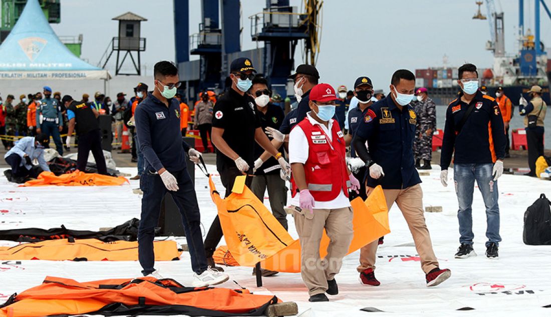 Petugas membawa kantong berisi jenazah dan serpihan dari pesawat Sriwijaya Air SJ182 yang dievakuasi ke Dermaga JICT 2, Jakarta Utara, Minggu (10/1). - JPNN.com
