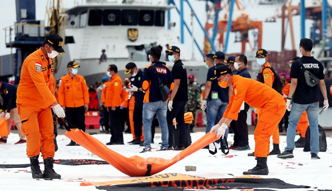 Petugas membawa kantong berisi jenazah dan serpihan dari pesawat Sriwijaya Air SJ182 yang dievakuasi ke Dermaga JICT 2, Jakarta Utara, Minggu (10/1). - JPNN.com